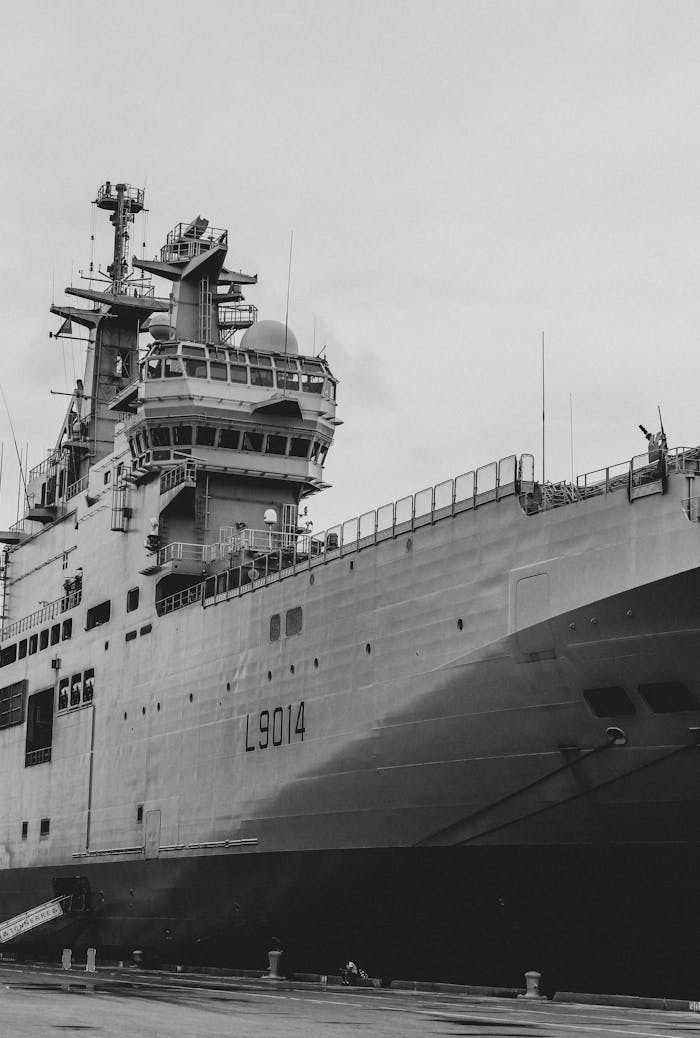 Black and white photo of a military ship docked in Cartagena harbor, showcasing its massive structure.